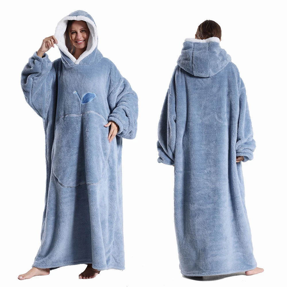 Deux vues d’une couverture-hoodie oversize bleue en sherpa portée par une femme ; capuche doublée blanche et grande poche kangourou visible.