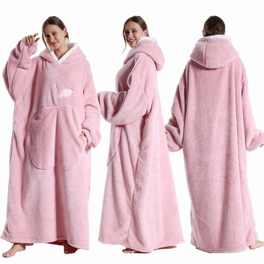 Deux vues d’une couverture-hoodie oversize rose en sherpa portée par une femme ; capuche doublée blanche et grande poche kangourou visible.